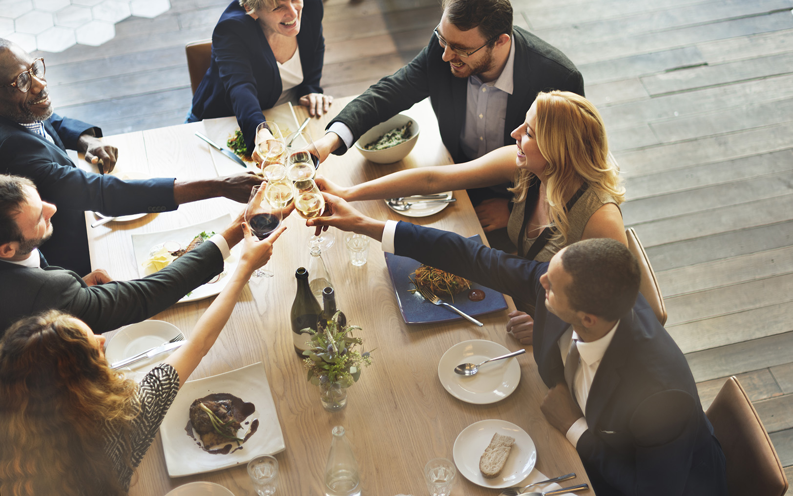 a group of people happily toasting at a dinner table