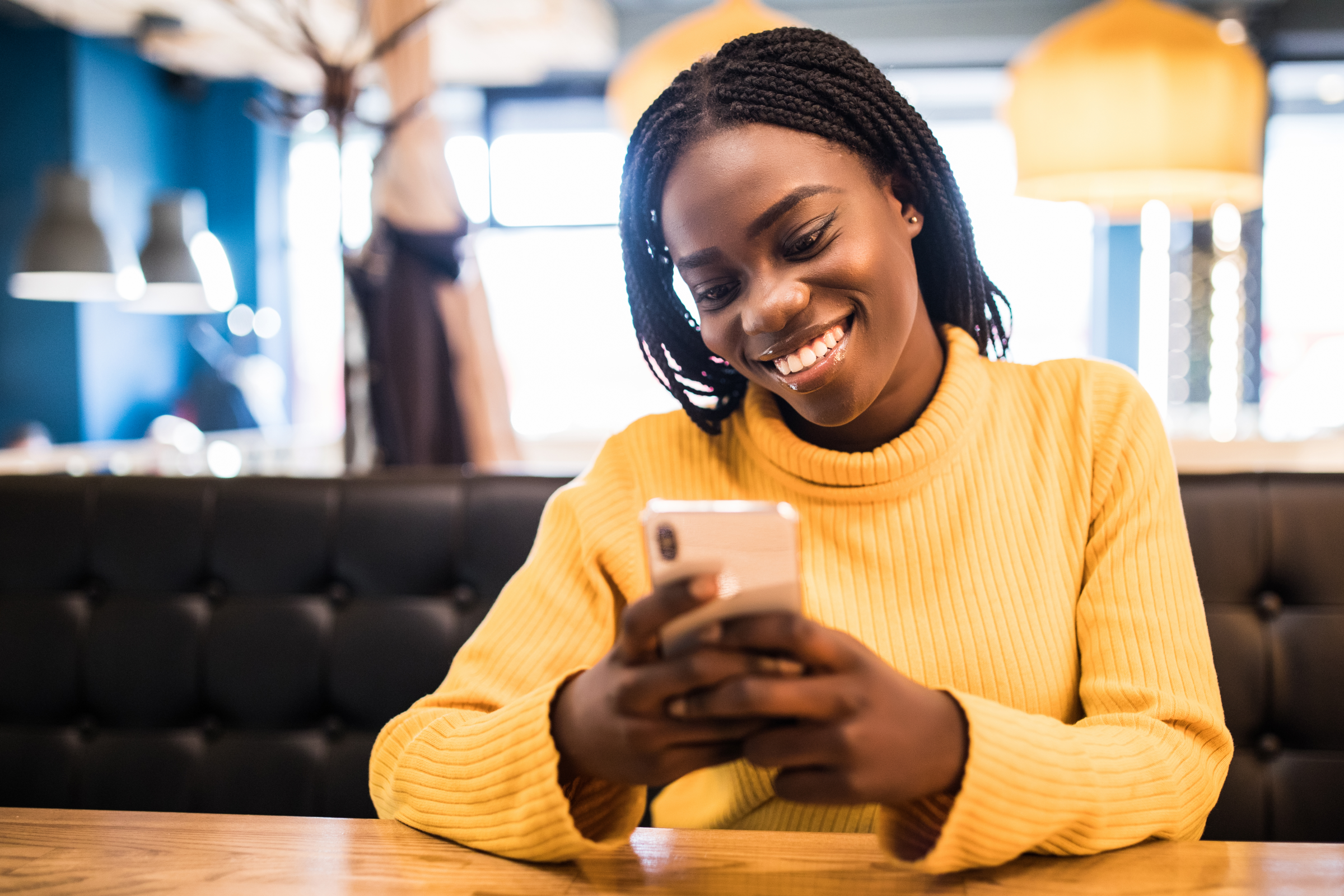 Young African American woman in a yellow turtleneck sits at a table